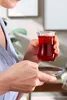 A person holding a glass of red tea and a saucer. Náhľad obrázku produktu
