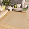 An outdoor living space with a sofa, chairs, a coffee table, and a large rug on a wooden deck. Produktbild-Vorschau