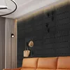 A modern living room with a black wall panel, a tan sofa, and a floor lamp. Náhled obrázku produktu