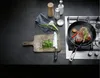 A steak is being seared in a pan on a gas stovetop, with chopped herbs and cooking ingredients nearby. Náhľad obrázku produktu