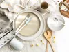 A table setting with plates, cutlery, a mug, and salad servers, decorated with small daisy-like flowers. Náhľad obrázku produktu