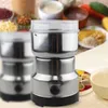 A silver electric spice grinder sits in the foreground with various spices and ingredients blurred in the background. Produktbild-Vorschau