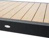 A close-up view of a section of an outdoor table with a wooden slatted surface and a dark frame. Produktbild-Vorschau