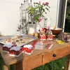 A table set up outdoors with Christmas cookies, baking supplies, and decorations. Produktbild-Vorschau