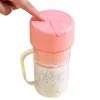 A hand is pressing the button on the lid of a portable electric juicer filled with a white smoothie with black seeds. Produktbild-Vorschau