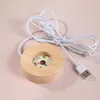 A close-up shot of a wooden LED lamp base with a USB cable and a white switch. Náhled obrázku produktu
