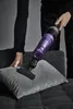 A person is vacuuming a pillow on a sofa with a purple and black stick vacuum cleaner. Voir les images du produit