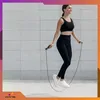 A woman is jumping rope in front of a tiled wall. Podgląd zdjęcia produktu