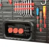 A close-up view of a tool storage system with various tools mounted on it, including wrenches, screwdrivers, and a cable winder. Produktbild-Vorschau