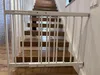 A white baby gate is installed at the bottom of a wooden staircase. Voir les images du produit