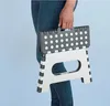 A person is holding a folded step stool. Podgląd zdjęcia produktu