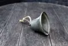 A metal bell with a rope attached lies on a dark wooden surface. Anteprima dell’immagine prodotto