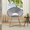 A gray velvet accent chair with gold metal legs is placed in a room with a large window and sheer curtains. Produktbild-Vorschau