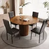 A round wooden dining table with four black chairs set up in a dining room. Náhled obrázku produktu
