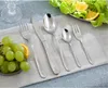 A set of silverware is arranged on a table with grapes and salad in the background. Produktbild-Vorschau