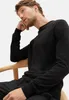 A man wearing a black sweater is sitting on a chair. Produktbild-Vorschau