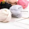 Several balls of colorful wool are arranged on a white wooden surface, with felting needles inserted into one of the balls. Produktbild-Vorschau