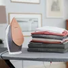 An iron and a stack of neatly folded clothes on an ironing board. Náhled obrázku produktu