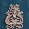 A close-up shot of a decorative bronze door knocker mounted on a dark teal wooden door. Produktbild-Vorschau