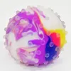 A close-up studio shot of a colorful, spiky stress ball. Produktbild-Vorschau