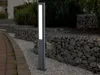 A modern LED bollard light is positioned on a gravel path next to a gabion wall filled with stones. Anteprima dell’immagine prodotto