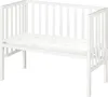 A white wooden crib with a mattress inside, shown from a side angle against a white background. Produktbild-Vorschau
