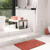 A modern bathroom with a bathtub, steps, and a small trash can. Náhľad obrázku produktu