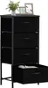 A black fabric dresser with four drawers is shown against a white background. The top drawer is slightly ajar, revealing some contents. Two framed pictures and a potted plant are placed on top of the dresser. Podgląd zdjęcia produktu