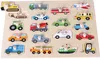 A wooden puzzle board with various vehicle shapes cut out, each with a peg for easy handling. Produktbild-Vorschau
