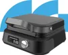 A modern black waffle maker with a digital display and a silver dial, set against a background of blue and white geometric shapes. Náhľad obrázku produktu