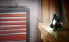 A work light is placed on a wooden workbench next to a tool chest in a workshop. Produktbild-Vorschau