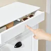 A close-up shot of a person's finger touching a white drawer of a cabinet, with sunglasses visible inside the drawer. Produktbild-Vorschau