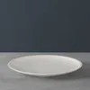 A white plate on a gray surface with a dark gray background. Podgląd zdjęcia produktu