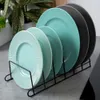 A set of colored plates displayed in a black metal rack on a kitchen counter. Produktbild-Vorschau