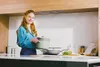 A woman is holding a cooking pot in a modern kitchen. Anteprima dell’immagine prodotto