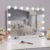 A Hollywood-style makeup mirror with LED lights is displayed on a white vanity table, reflecting a bedroom scene. Produktbild-Vorschau