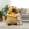 A young girl hugging a large capybara plush toy in a living room. Anteprima dell’immagine prodotto