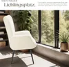 A cream-colored armchair is placed in a bright room with large windows overlooking trees. Bookshelves are visible in the background. Produktbild-Vorschau