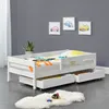 A white toddler bed with drawers underneath, set against a gray wall with framed car pictures. Náhľad obrázku produktu