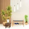 A shoe rack with a bench and cushion, placed in a hallway with plants and pendant lights. Produktbild-Vorschau