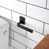 A black toilet paper holder mounted on a white tiled wall next to a toilet. Anteprima dell’immagine prodotto