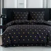 A neatly made bed with black bedding featuring a pattern of golden hearts. Produktbild-Vorschau