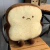 A plush toy shaped like a slice of toast sits on a wooden chair. Náhľad obrázku produktu
