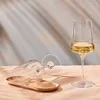 Two wine glasses are shown, one upright with white wine and another lying on its side on a wooden tray. Produktbild-Vorschau