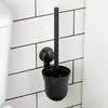 A black toilet brush and holder mounted on a tiled wall next to a toilet. Anteprima dell’immagine prodotto