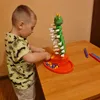 A young boy is playing with a toy caterpillar game on a wooden table. Náhľad obrázku produktu
