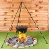A campfire with a pot hanging over it on a tripod stand. Produktbild-Vorschau