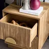A close-up view of a wooden nightstand with an open drawer. Produktbild-Vorschau