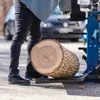 A person is standing next to a log splitter with a log on it. Produktbild-Vorschau