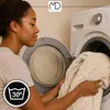A woman is putting a beige blanket into a washing machine. Anteprima dell’immagine prodotto